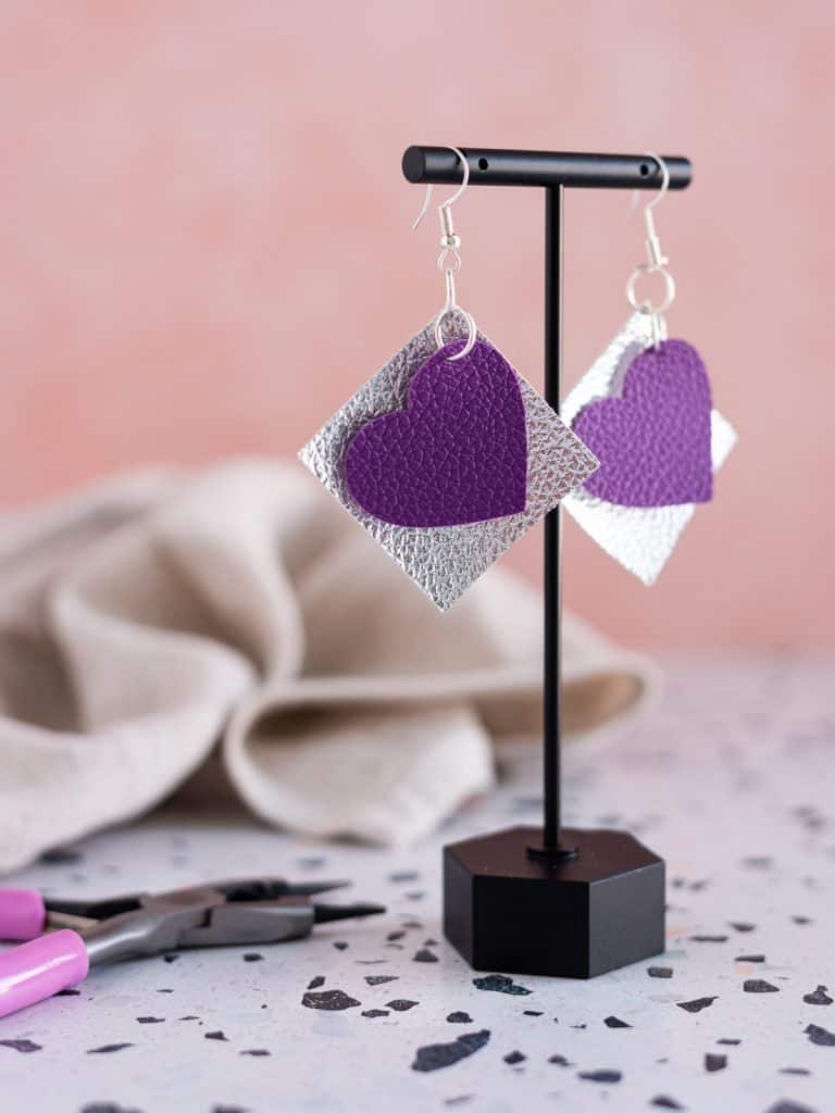 Purple faux leather heart earrings with a silver square behind them